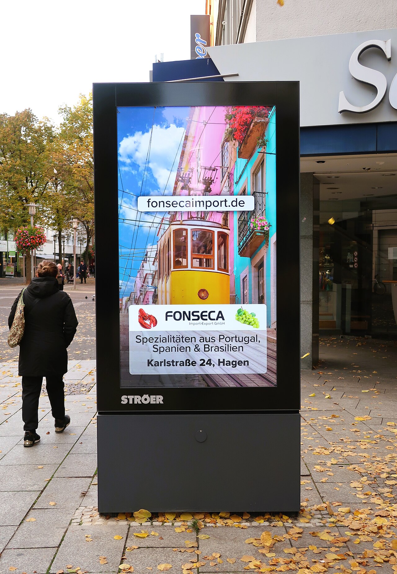 Digitaler Werbeaufsteller an einer Straßenecke in Hagen mit Anzeige eines Importgeschäfts
