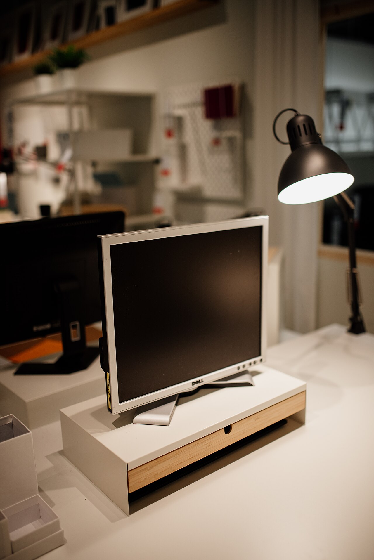 Schreibtisch mit Dell-Monitor, Lampe und Kartons in einem Büro