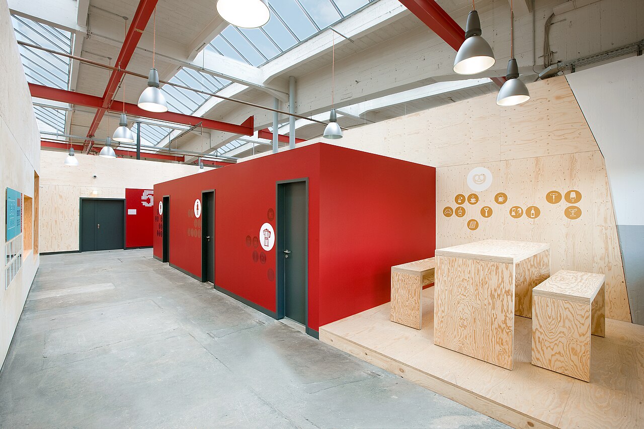 Leere Coworking-Lounge mit rotem Einbau und Holzmöbeln