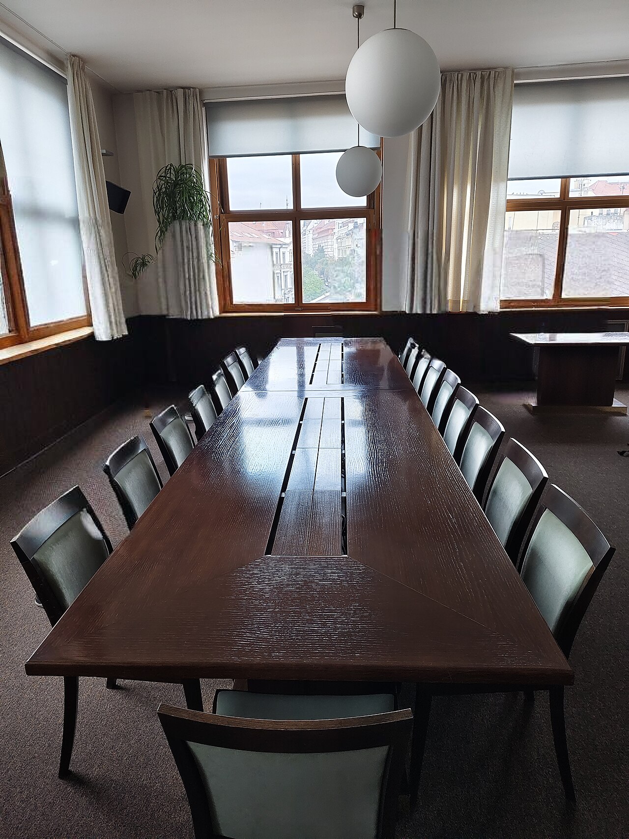Sitzungszimmer mit langem Konferenztisch und dunkelgrünen Stühlen
