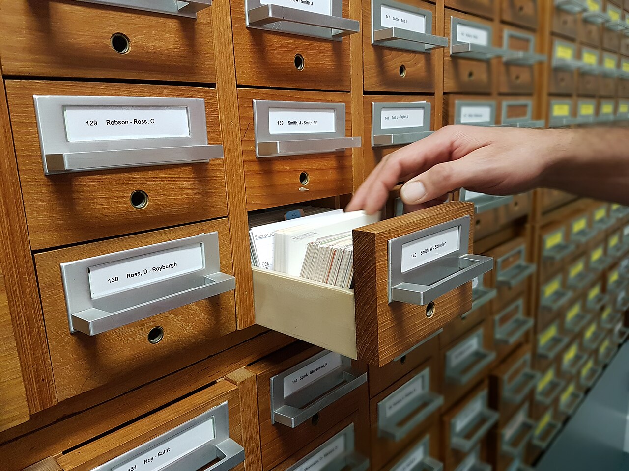 Hand zieht eine Schublade mit Karteikarten aus einem Aktenschrank