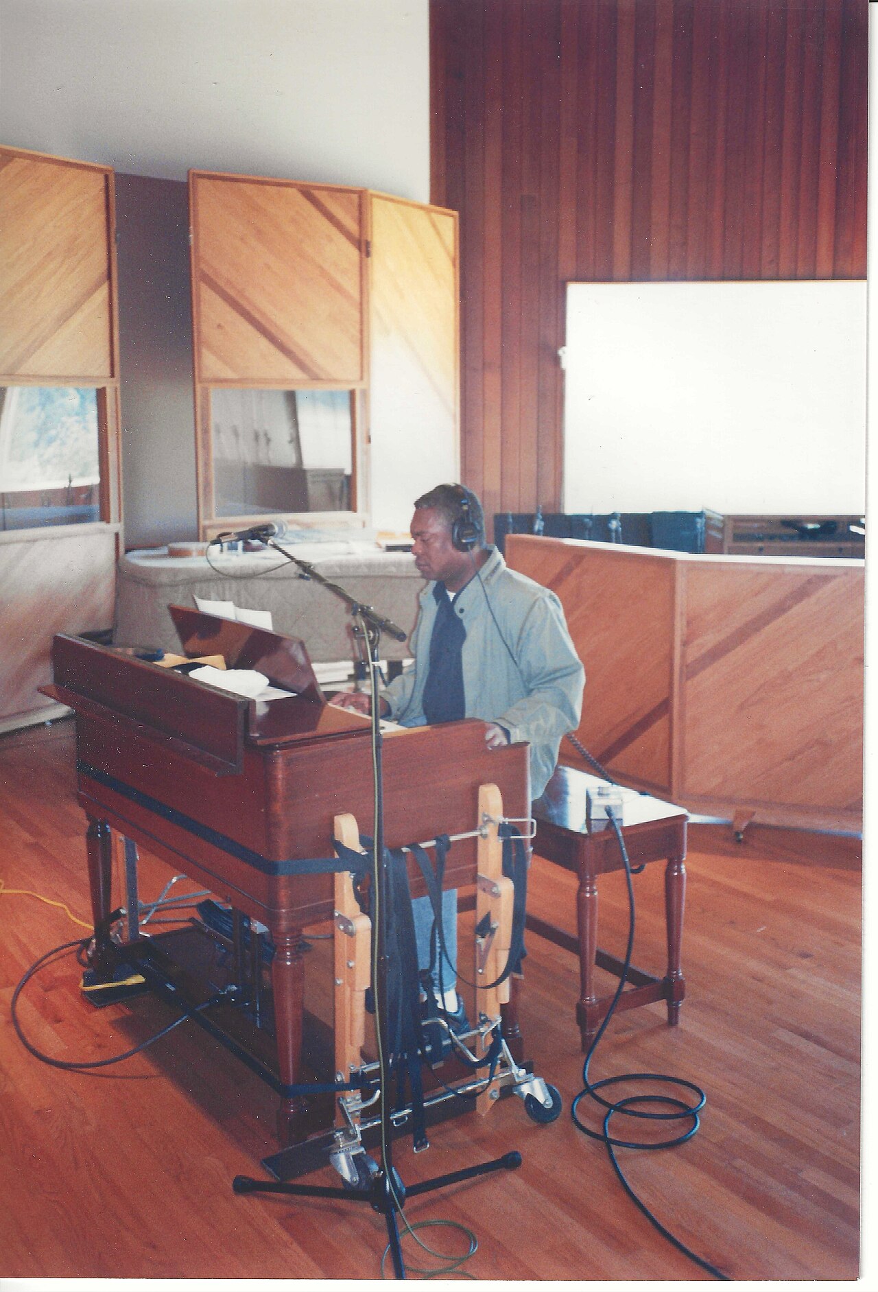 Musiker mit Kopfhörern an einem Tasteninstrument in einem Tonstudio, davor ein Mikrofonständer