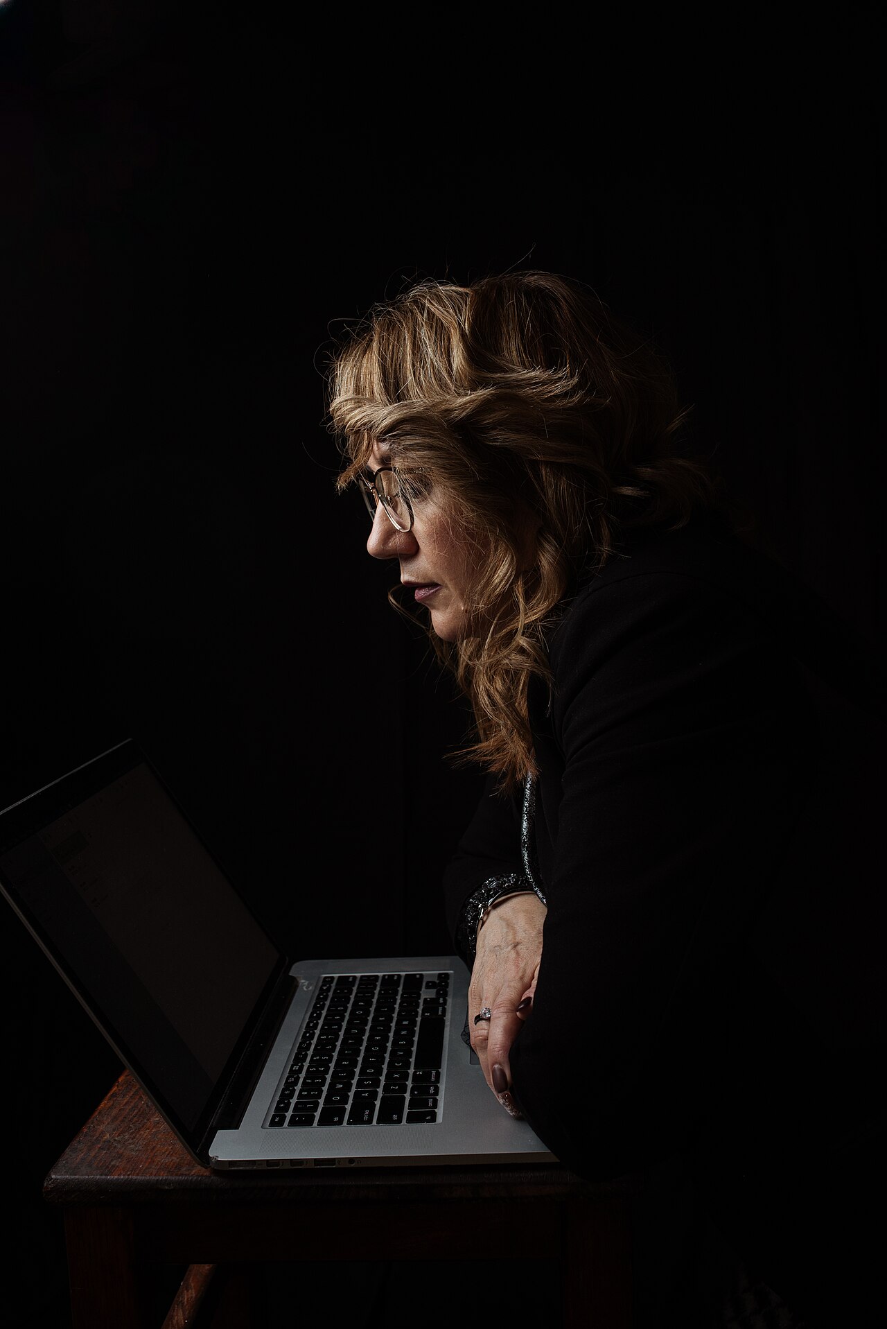 Frau arbeitet konzentriert am Laptop in dunkler Umgebung