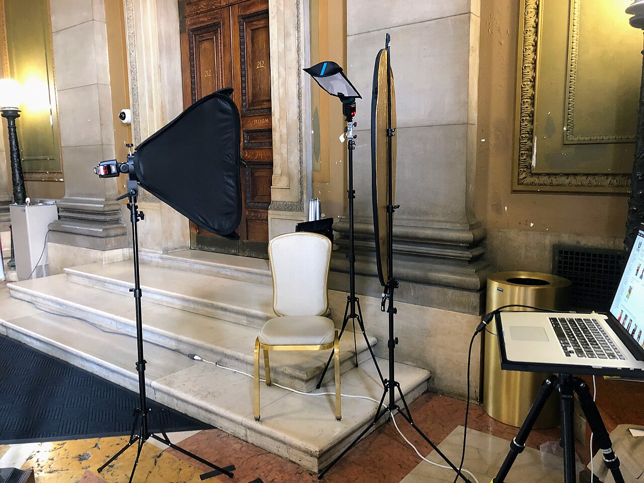 Fotostudio mit Stuhl, Beleuchtung und Laptop vor einer Treppe