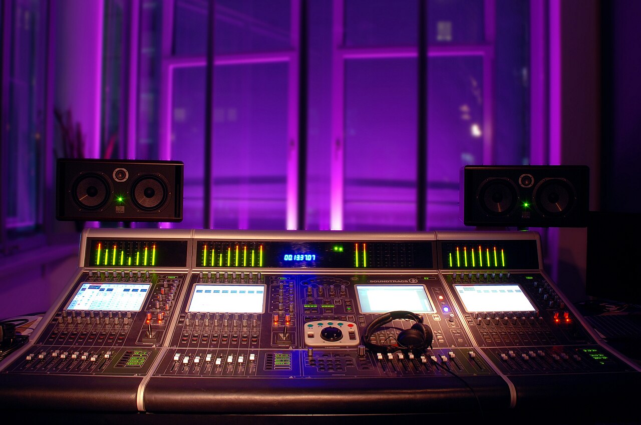 Mischpult in einem Tonstudio mit beleuchteten Reglern und Monitoren