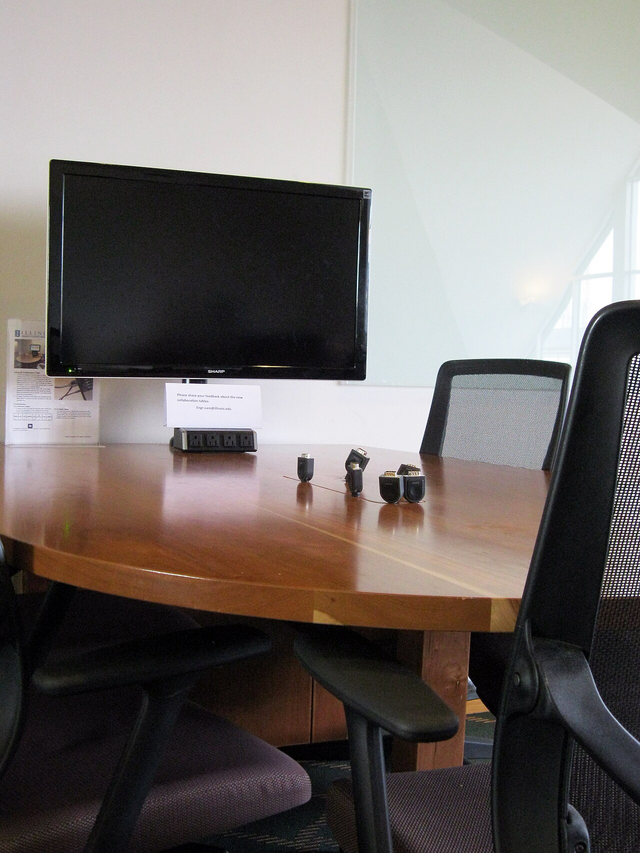 Arbeitsplatz mit Monitor, Adaptern und Bürostühlen